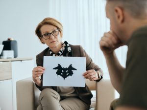 Mature psychiatrist evaluating mental disorder of soldier with inkblot test during counseling.