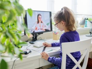 Girl child studying at home using a computer for video lesson