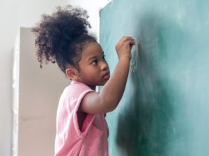 Kid write on chalk board. Back to school. Schoolchild in class. Happy kid writing green blackboard.