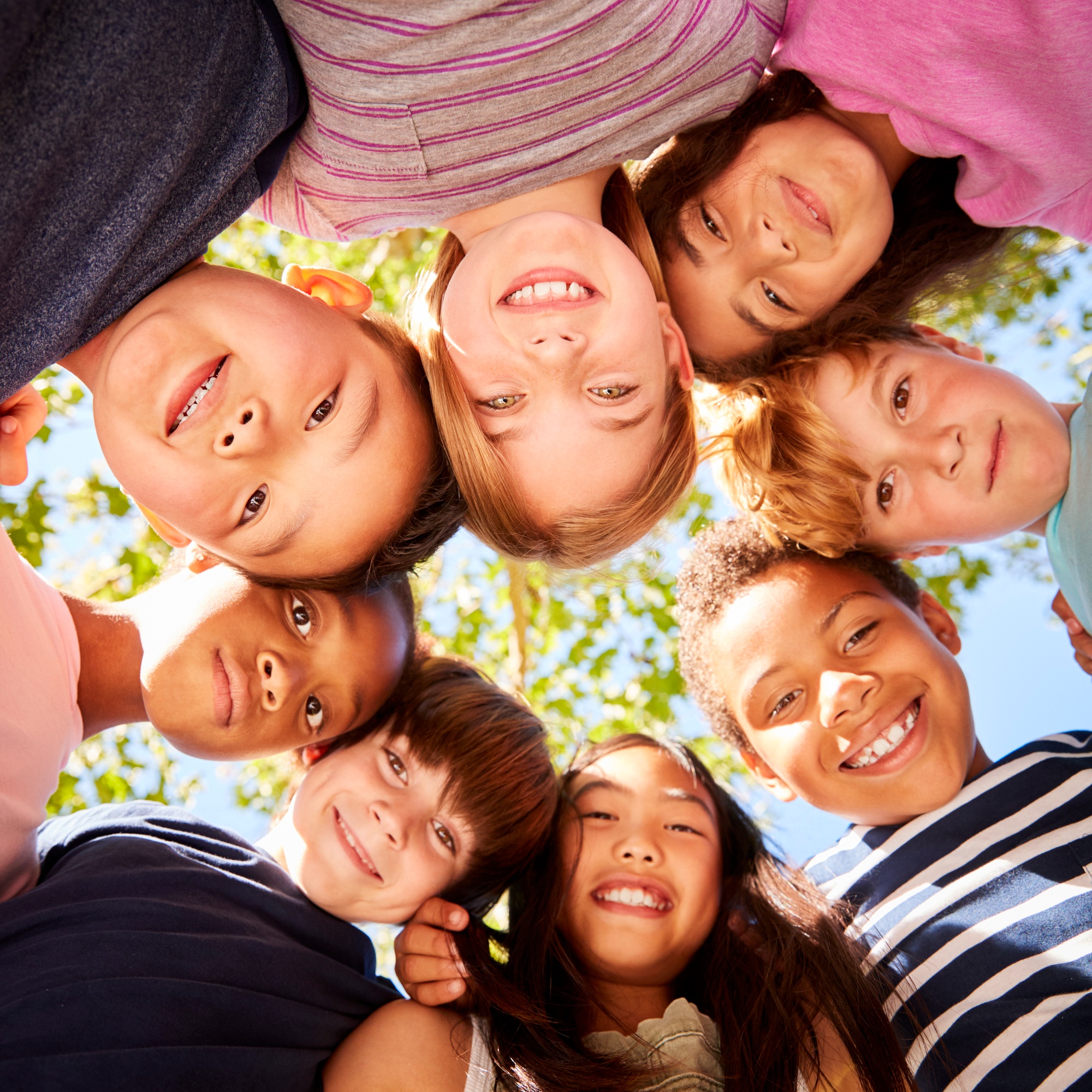 Group of kids outdoors looking down at camera, square format
