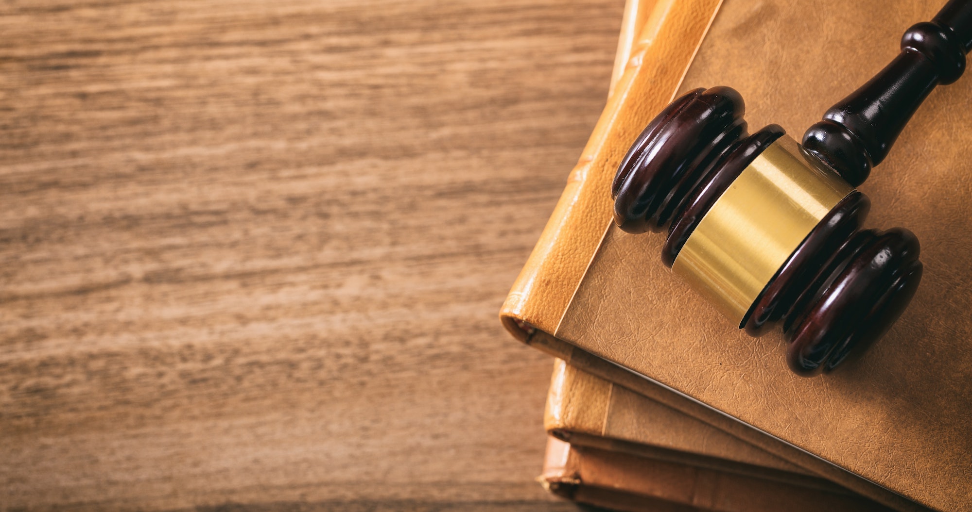 Judge gavel on law books, wooden desk, top view