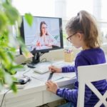 Girl child studying at home using a computer for video lesson