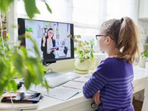 Girl child studying at home using a computer for video lesson