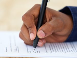 Shot of an unrecognisable businessman filling in a form on a desk in an office